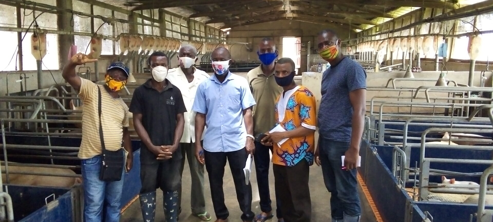 Sierra Leonean trainees in Ghana with ARI Graduate John Yeboah, posing in a pig house.